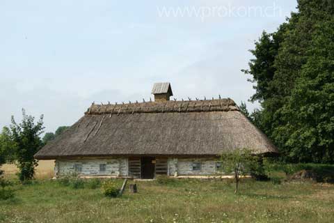 Ein grössere Blockhaus, mit Strohdach. Im mittleren Teil hat's Geräte, links und rechts Wohn- und Arbeitsräume.